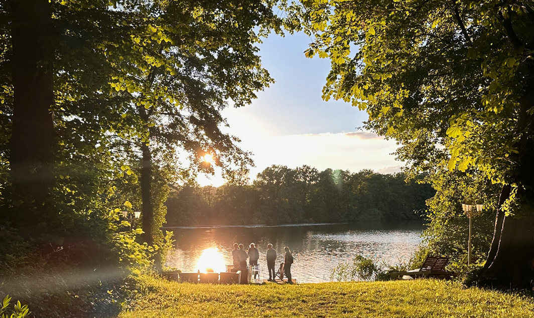 Kleine Gruppe von Menschen unter Bäumen am See