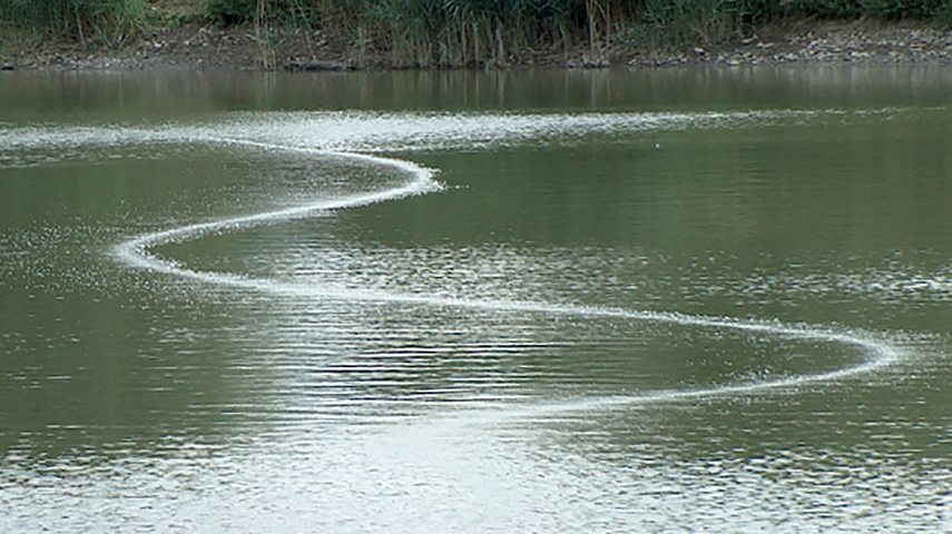 Trace de bulle en forme de S sur un lac - c'est l'indication d'un système Drausy® - l'aération a lieu au fond de l'eau, on reconnaît une trace de bulle en surface