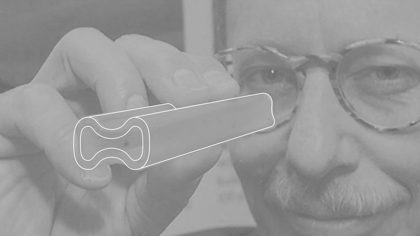 Coupe transversale du système de ventilation Drausy® Professional - le fondateur Nikolaus Weth tient une section du système linéaire devant son œil et regarde à travers comme à travers une lunette.