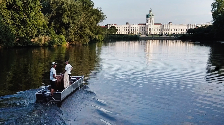 Vue du château de Charlottenburg Berlin, depuis l'étang de carpes - à gauche de l'image, on reconnaît le bateau d'épandage Drausy® - le bateau se promène sur l'ensemble du plan d'eau pour distribuer des sous-segments de la ligne d'aération.