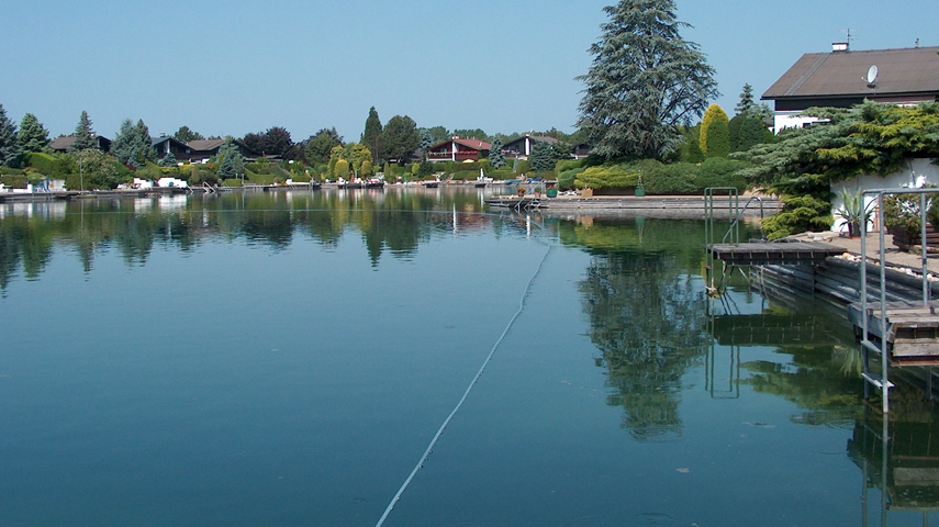 View of Maderna Pond - the surface of the water is as smooth as glass, you can see some terraces of the surrounding houses on the banks